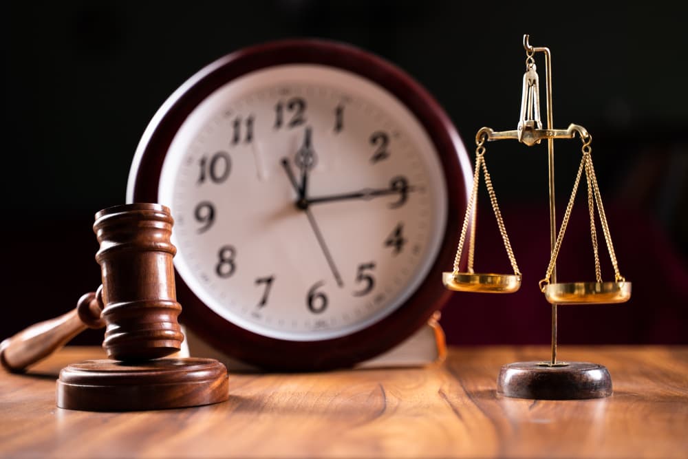 Justice Scale and gavel on wooden floor while clock in background