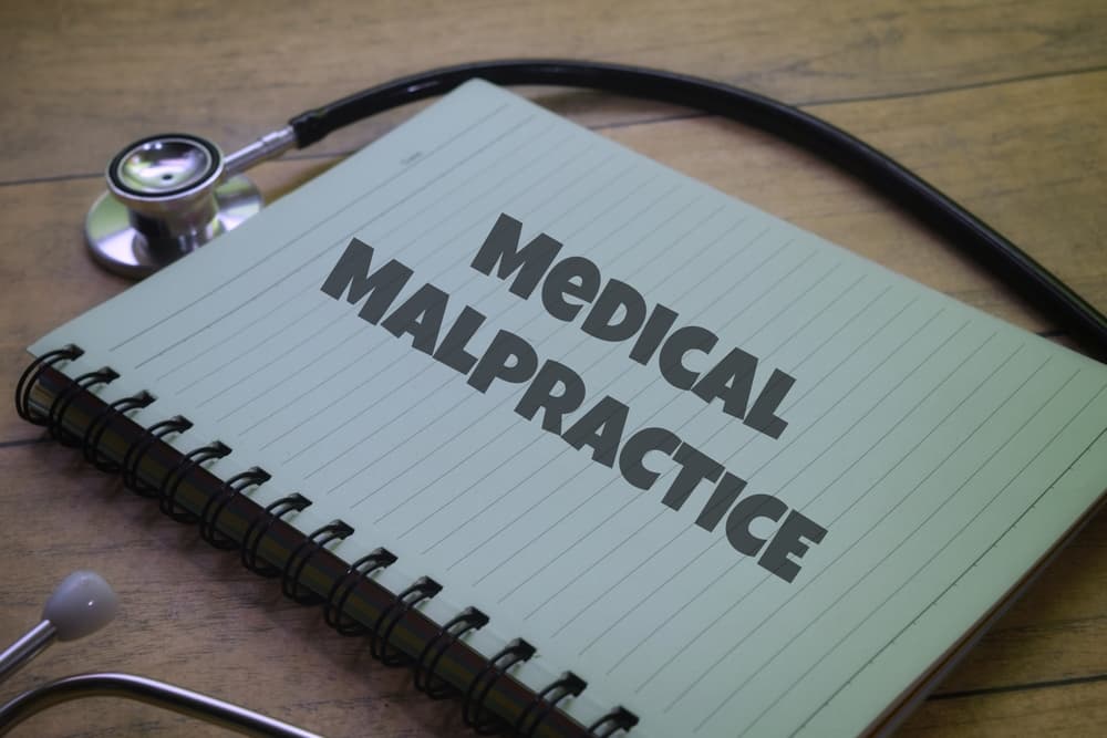 Medical Malpractice wording on a book with stethoscopes.