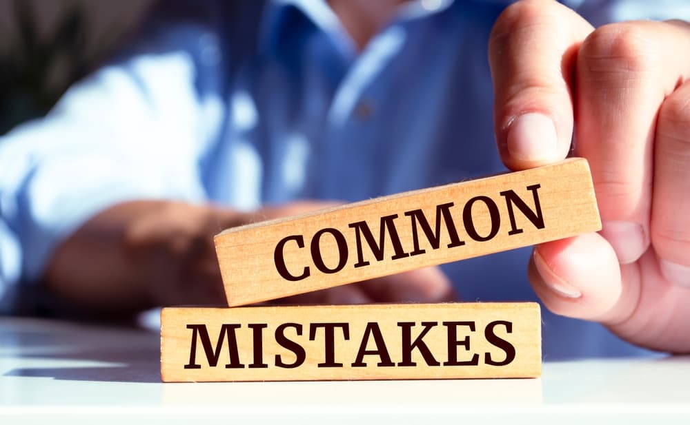 Common Mistakes word in wooden block holding by a man with his fingers
