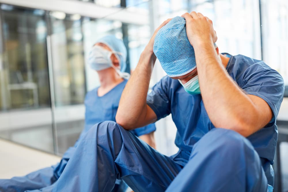 Two exhausted and desperate surgeons as signs of congestion and error