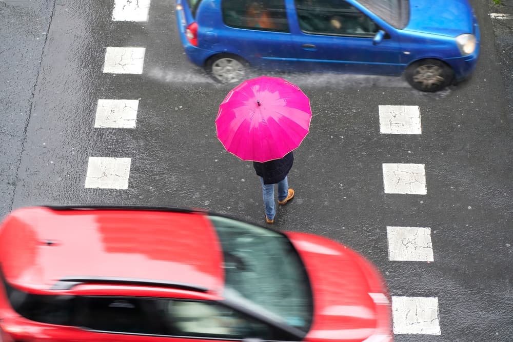 People pedestrian in rainy situation in crosswalk in city street by vehicles at high speed
