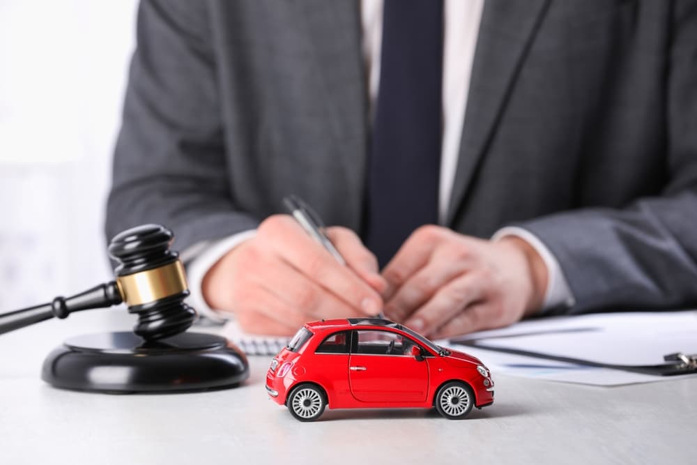 Auto accident law. Lawyer working at table indoors, focus on toy car