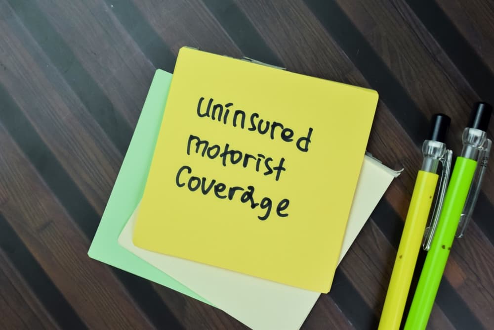 Uninsured Motorist Coverage write on sticky notes isolated on Wooden Table.