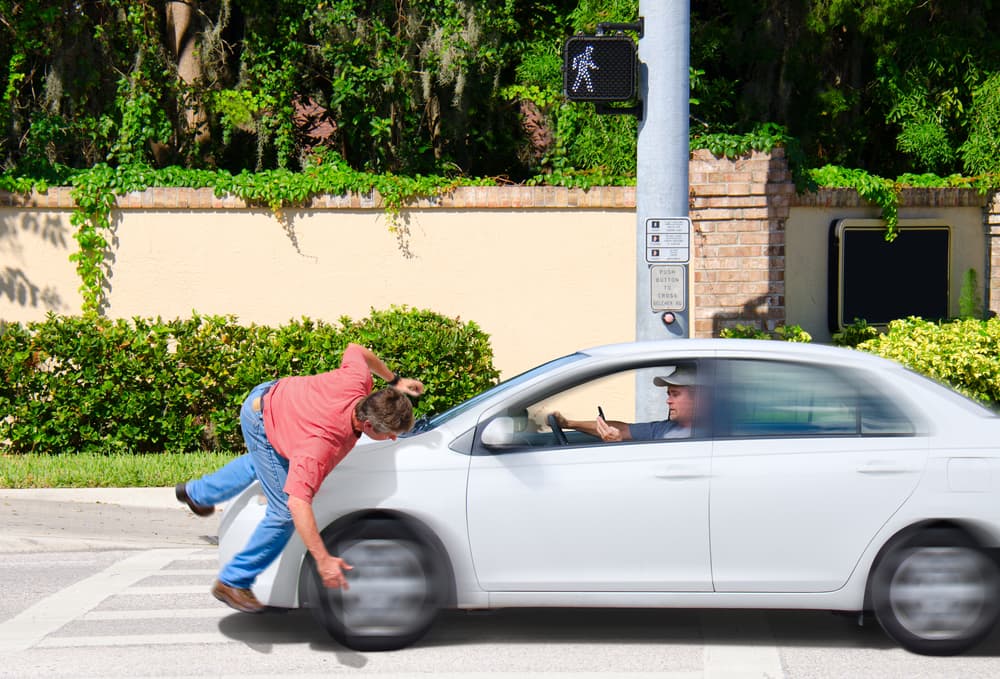 A man that is texting while driving runs over a pedestrian while the Cross